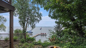 Ein Seezaun mit Feuerstelle, eine Anlegestelle mit Stühlen und Blick auf den See.