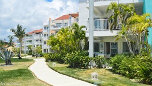 Un complexe hôtelier composé de bâtiments à plusieurs étages, doté de balcons et d’une végétation tropicale luxuriante.