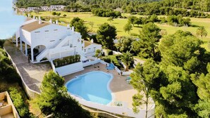 A large white building with a swimming pool, surrounded by lush greenery and hills in the background. - Flat Surrounded by Nature, With Pool, and Beach Nearby (Son Parc)