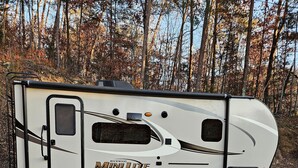 A Rockwood Mini Live RV parked on gravel with a forest background. - Barbara's little camper! (Sevierville)