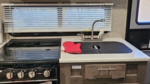 A compact kitchen with a stove, oven, microwave, and a small sink. - Barbara's little camper! (Sevierville)