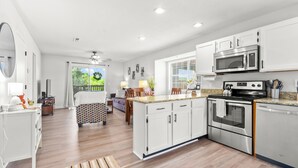 A modern kitchen with white cabinets, stainless steel appliances, and a large island.