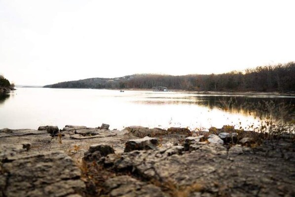 A rocky shoreline with a calm lake and distant hills.