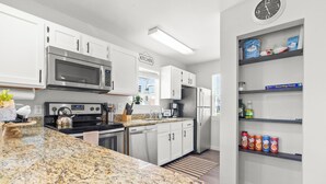 A modern kitchen with white cabinets, stainless steel appliances, and granite countertops.