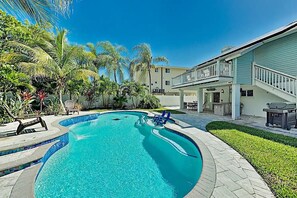 A swimming pool with a curved edge, surrounded by a patio area with chairs and a barbecue grill. - 408 Harbor Dr S – Heated Pool Home w/ Outdoor Kitchen, Walk to Beach & Dining (Indian Rocks Beach)