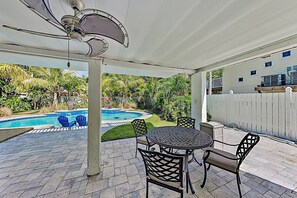 A covered patio with a pool, outdoor furniture, and a view of a residential area. - 408 Harbor Dr S – Heated Pool Home w/ Outdoor Kitchen, Walk to Beach & Dining (Indian Rocks Beach)
