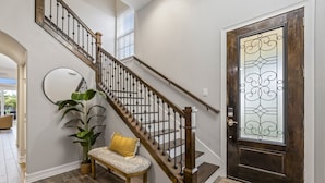 A staircase with wooden balusters and a dark wooden door with decorative glass panels.