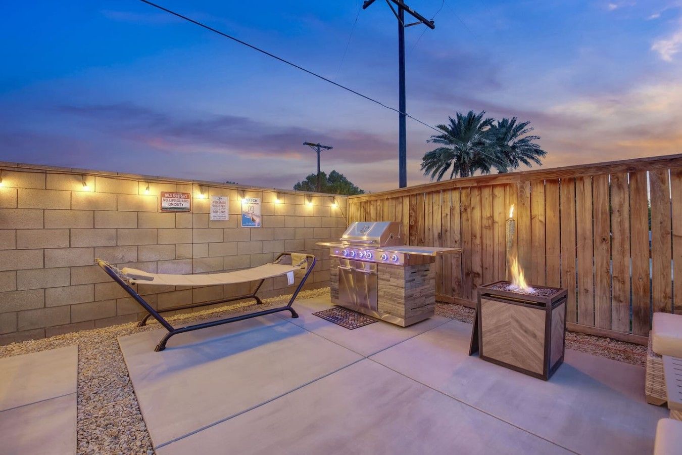 An outdoor patio area with a barbecue grill, a cushioned seating area, and a fire pit.