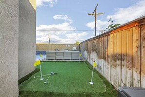 A backyard with artificial turf, a pool, and a wooden fence. - Park Heaven: Pool, Spa, Fire Pit, Games, BBQ! (Coachella)