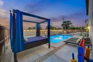 A poolside area with a canopy bed, lounge chairs, and a small pool. - Park Heaven: Pool, Spa, Fire Pit, Games, BBQ! (Coachella)