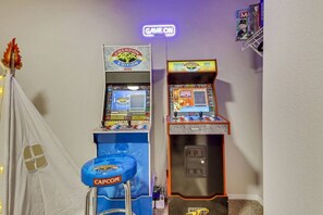 Two arcade machines, a neon sign, and a small tent-like structure with a blue seat. - Park Heaven: Pool, Spa, Fire Pit, Games, BBQ! (Coachella)