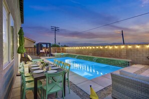 A backyard with a swimming pool, outdoor seating, and a pergola.