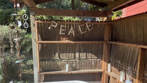 A wooden outdoor spa area with a bathtub, wooden shelves, and a 'PEACE' sign.