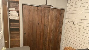 A bathroom with a wooden door, a sink, and a tiled wall.