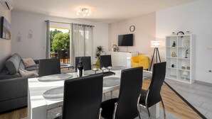 Un salon moderne comprenant un coin repas, un canapé, un téléviseur et une bibliothèque.