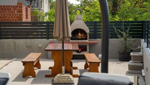 Une terrasse extérieure dotée d’un four à pizza au bois, de tables et de bancs en bois.