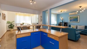 Een moderne keuken met blauwe kastjes, een houten aanrecht en een eethoek met een tafel en stoelen.