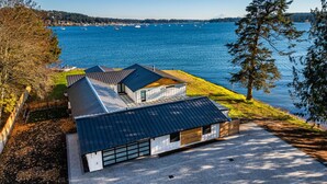 A modern house with a sloped roof, a garage, and a view of a lake with boats.