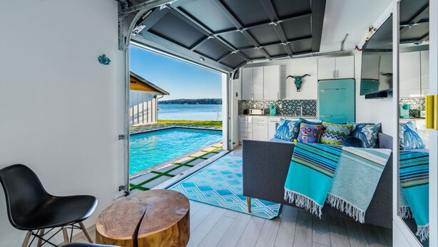A modern kitchen with white cabinets, a teal refrigerator, and a view of a swimming pool.