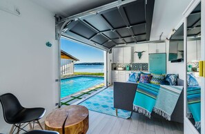 A modern kitchen with white cabinets, a teal refrigerator, and a view of a swimming pool. - Coastal Cabana ~ Poulsbo, WA  (Poulsbo)