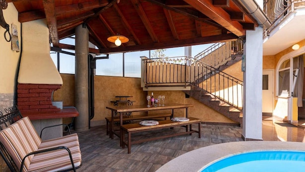 Un espacio exterior cubierto con piscina, una parrilla, una mesa de comedor con bancos y una escalera que lleva a un nivel superior.