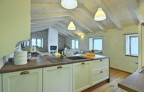 A spacious kitchen with a central island, white cabinets, and pendant lighting. - Stunning home in Buje (Buje)