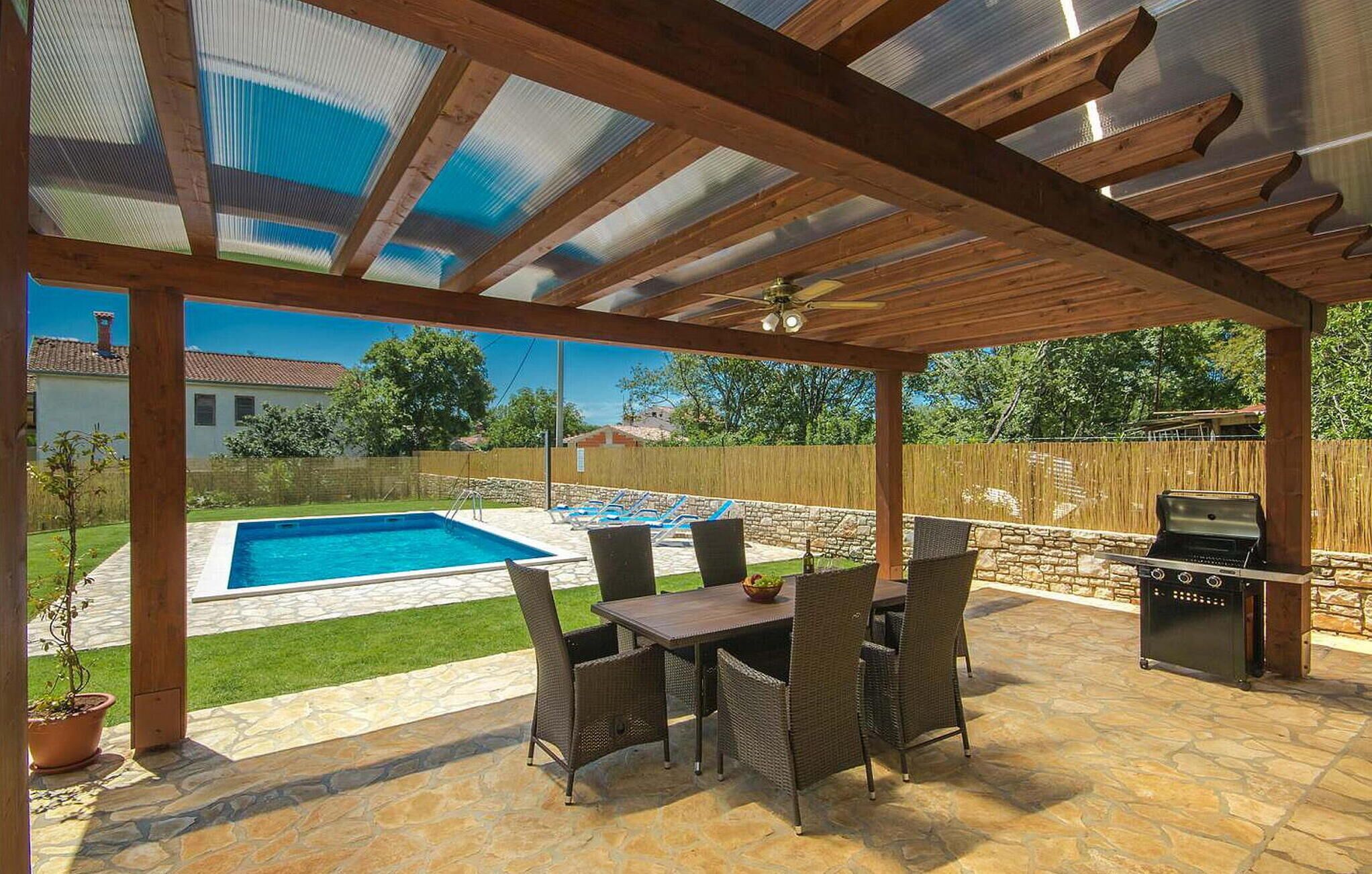 Una terrassa coberta amb piscina, mobiliari exterior i una barbacoa.