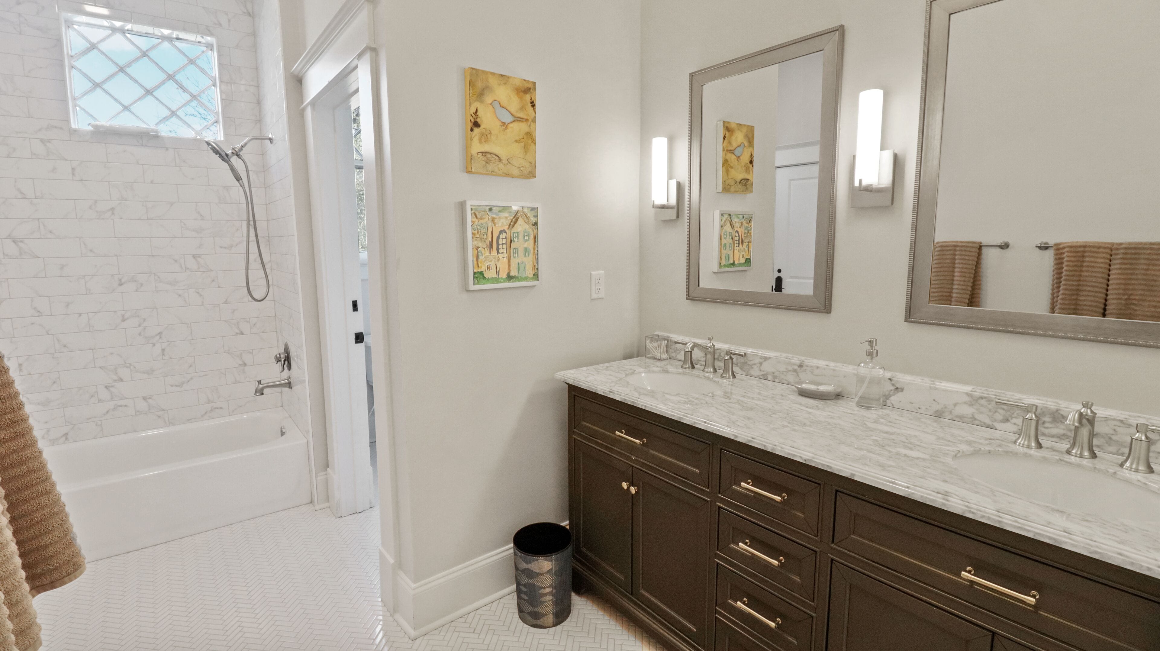 A bathroom with a bathtub, a large mirror, and a vanity with a sink.