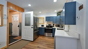 A modern kitchen with stainless steel appliances, blue cabinets, and a wooden floor. - Osprey Point - Lakefront Dock, Kayaks & Fire Pit (Cable)