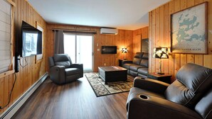 A wooden-paneled room with a sofa, two armchairs, a coffee table, a TV, and a map on the wall. - Osprey Point - Lakefront Dock, Kayaks & Fire Pit (Cable)