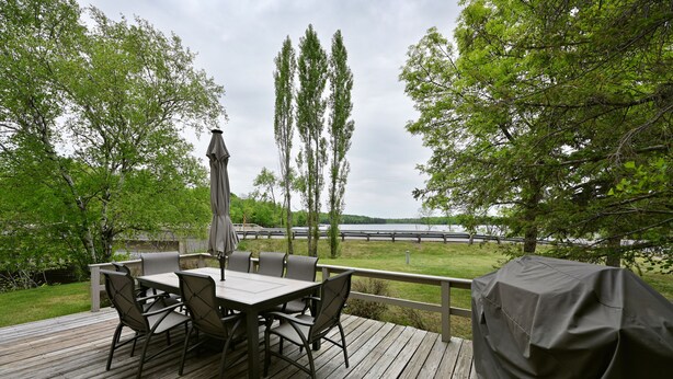 A wooden deck with a table and chairs, overlooking a body of water. - Osprey Point - Lakefront Dock, Kayaks & Fire Pit (Cable)