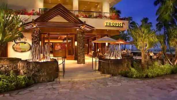 A hotel entrance with a tropical theme, including a sign that reads "TROPICS". - Waikiki | Waikiki Lagoon Escape | Pool & Beach | 2BR (Honolulu)