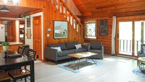 L’intérieur d’un chalet en bois comprend un coin repas, un canapé et un escalier.