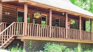 Une cabane en bois dotée d’une véranda, de fenêtres et de jardinières suspendues.
