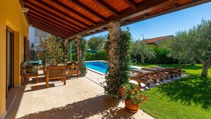 A covered outdoor area with a pool, wooden furniture, and potted plants. - Lovely home in Fazana (Fazana)