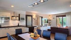 A modern kitchen with a dining area, a living room with a sofa, and a balcony with a view. - Lovely home in Fazana (Fazana)