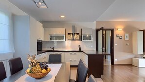 A modern kitchen with white cabinets, stainless steel appliances, and a dining area with a table set for four. - Lovely home in Fazana (Fazana)