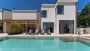 A modern two-story house with a swimming pool, lounge chairs, and a patio area. - 3 bedroom beautiful home in Porec (Porec)
