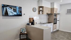 A modern kitchen with a central island, white cabinetry, a microwave, oven, and a coffee maker.