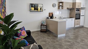 A modern apartment with a kitchen, living area, and a large potted plant.