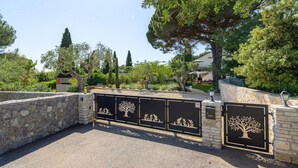 A gated entrance with stone walls and decorative metal gates featuring tree designs.