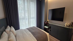 Una habitación de hotel con una cama, televisión, escritorio y una silla.