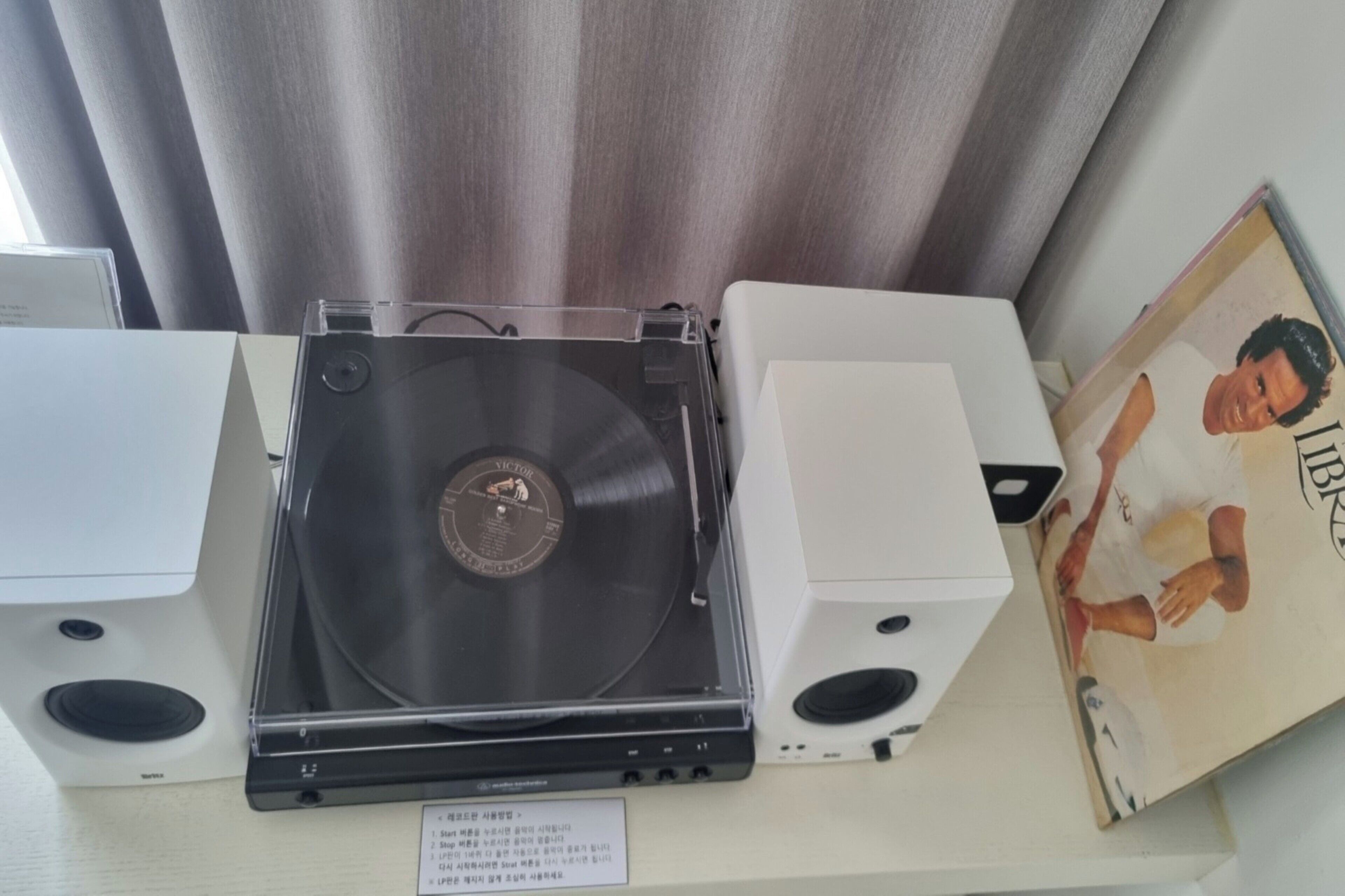 A turntable with a vinyl record, two speakers, and a framed picture on a table.