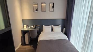 A hotel room with a bed, desk, chair, and three wall-mounted lights.