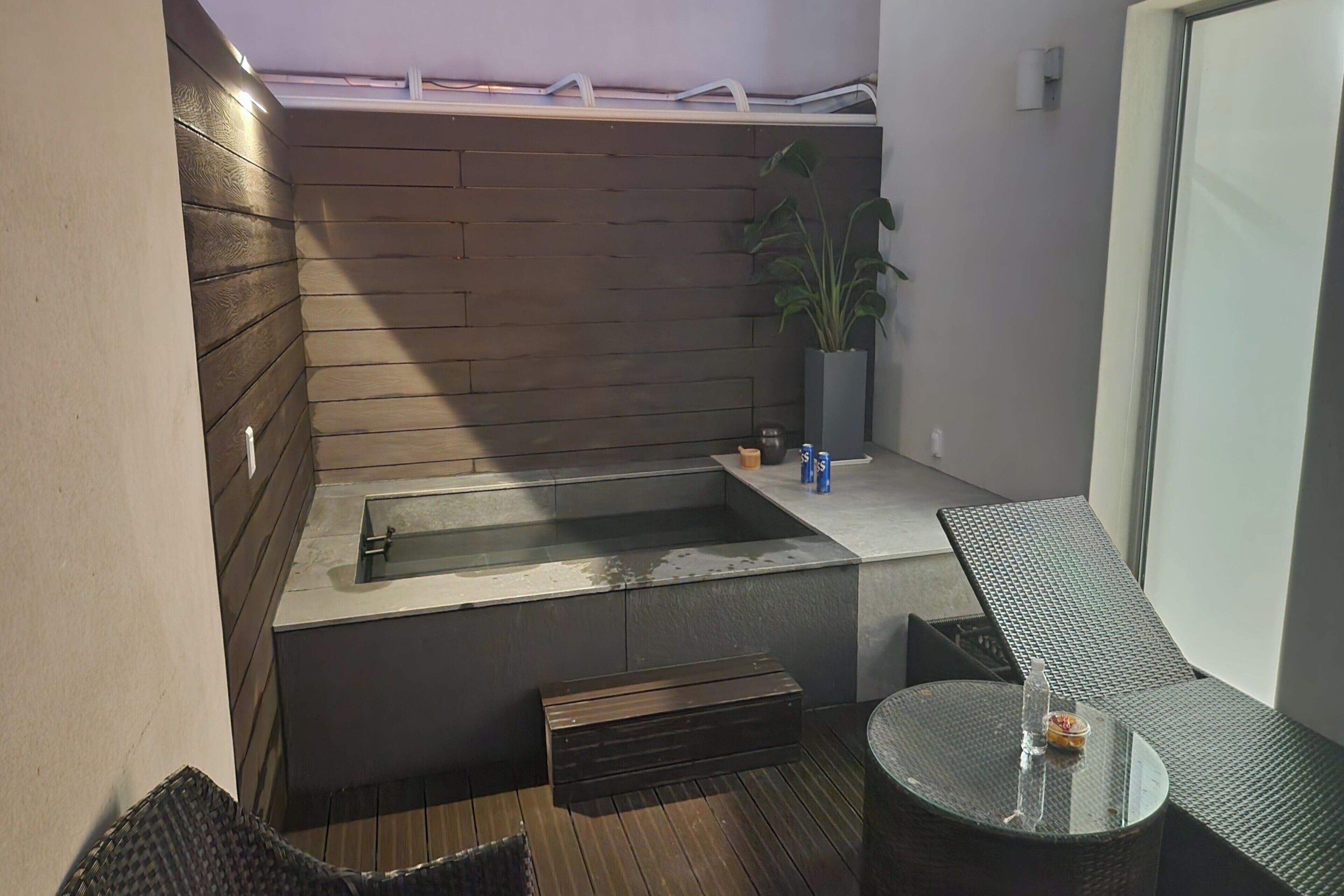 A small, enclosed outdoor area with a built-in bench, a small table, and a potted plant.