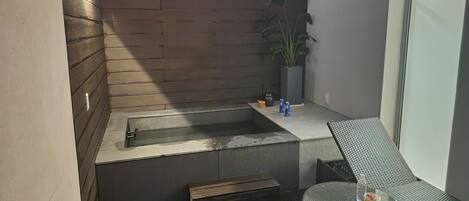 A small, enclosed outdoor area with a built-in bench, a small table, and a potted plant.