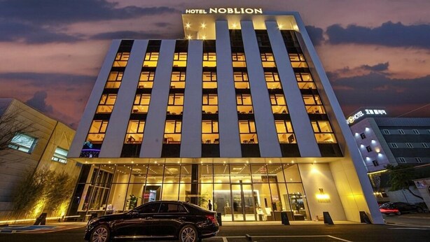 Un hotel de diseño moderno, con un letrero llamativo en la parte superior y una entrada amplia con puertas de vidrio.