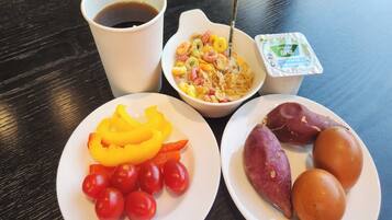 A table with a white plate of cherry tomatoes, a bowl of cereal, a cup of coffee, and a plate of sweet potatoes.