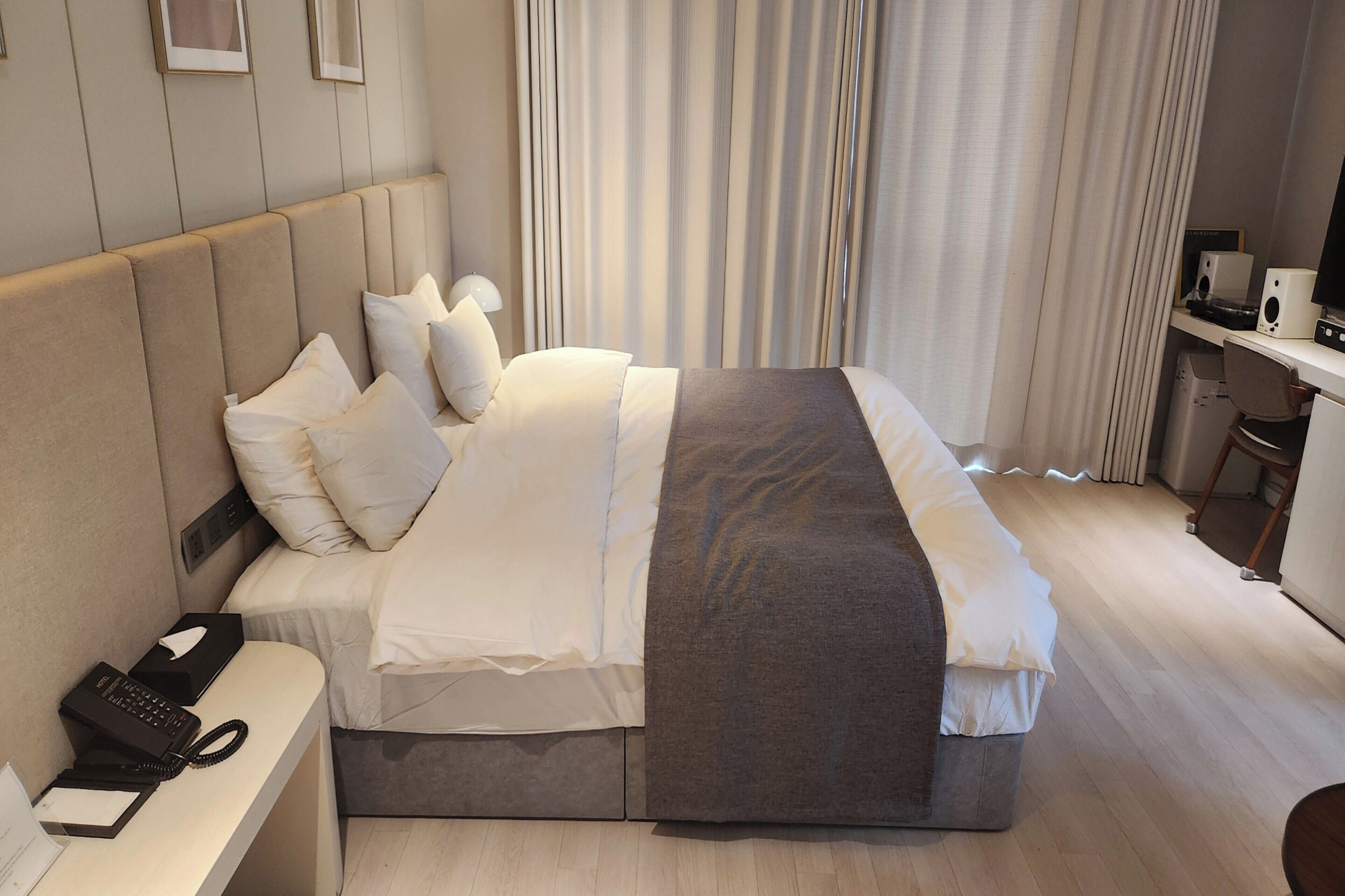 Ein Hotelzimmer mit Bett, Schreibtisch, Telefon und Stuhl.