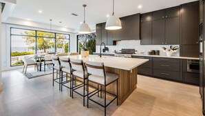 A modern kitchen with dark cabinets, a central island, and pendant lighting. - Pier Pleasure - Anna Maria at it's finest! Pool, hot tub, beach, putting green (Anna Maria)